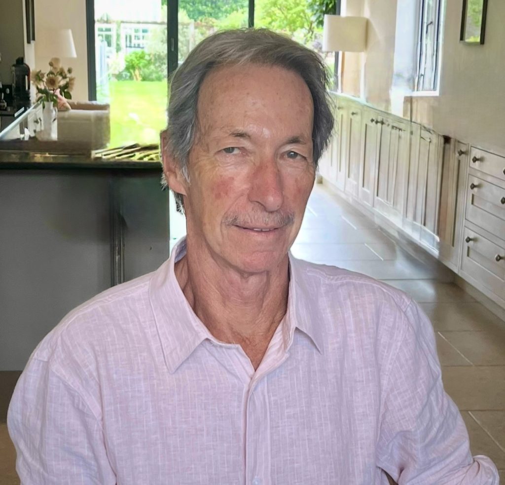 Head and shoulder image of a man wearing a pink shirt.