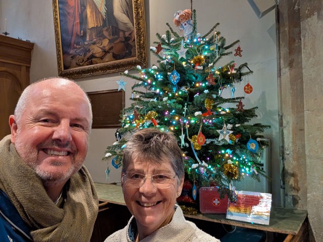 Man and woman in front of small decorated Christmas trees.