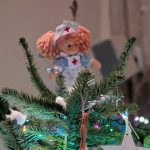 A toy doll dressed as a nurse on top of a Christmas tree.