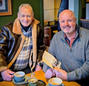 Two men sitting at a table in a coffee shop.