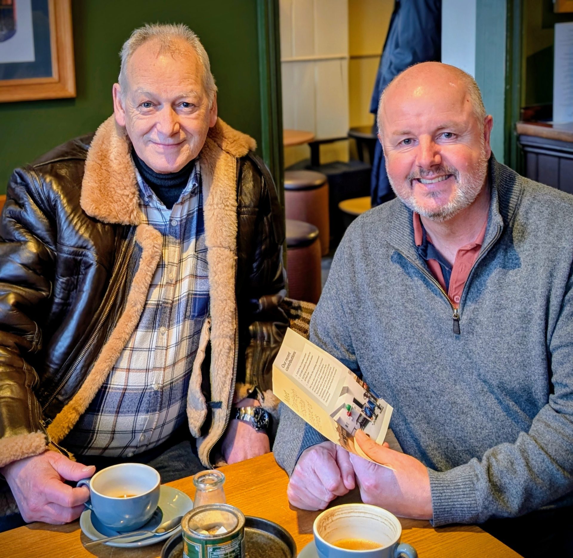 Two men sitting at a table in a coffee shop.